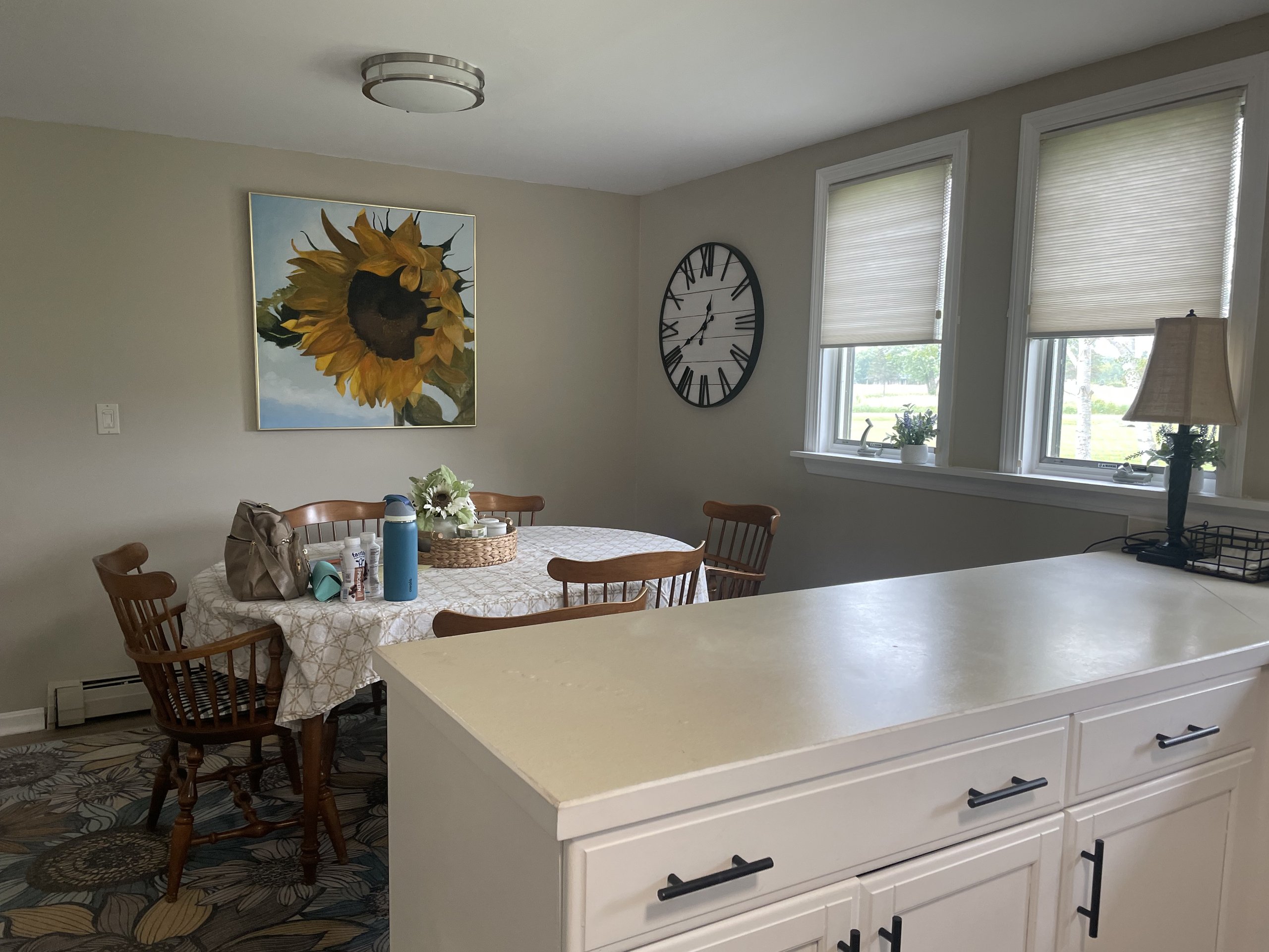 Breakfast nook with round table, farmhouse chairs, and an oversized wall clock