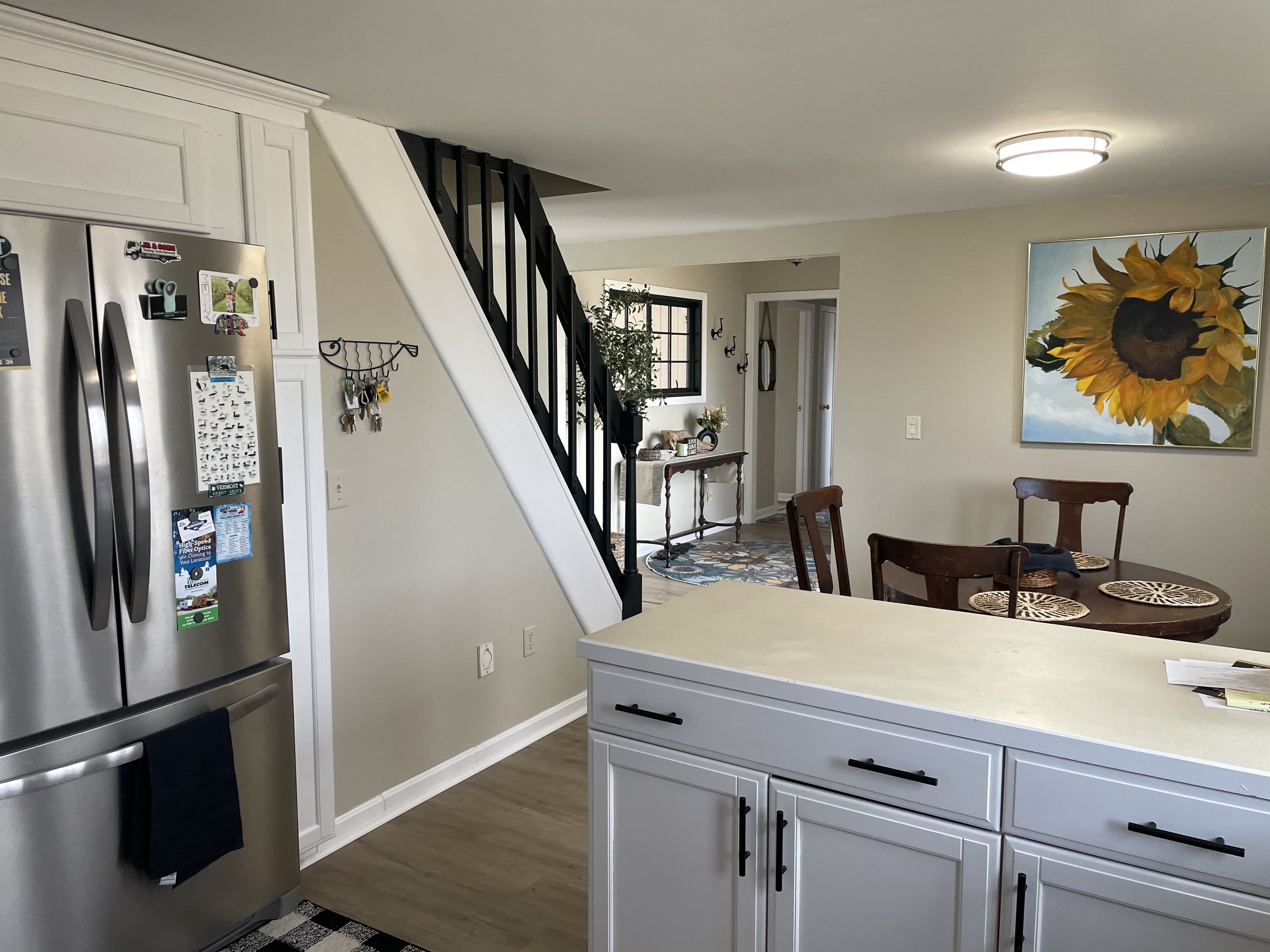 Kitchen opens onto a staircase and dining nook beyond the refrigerator