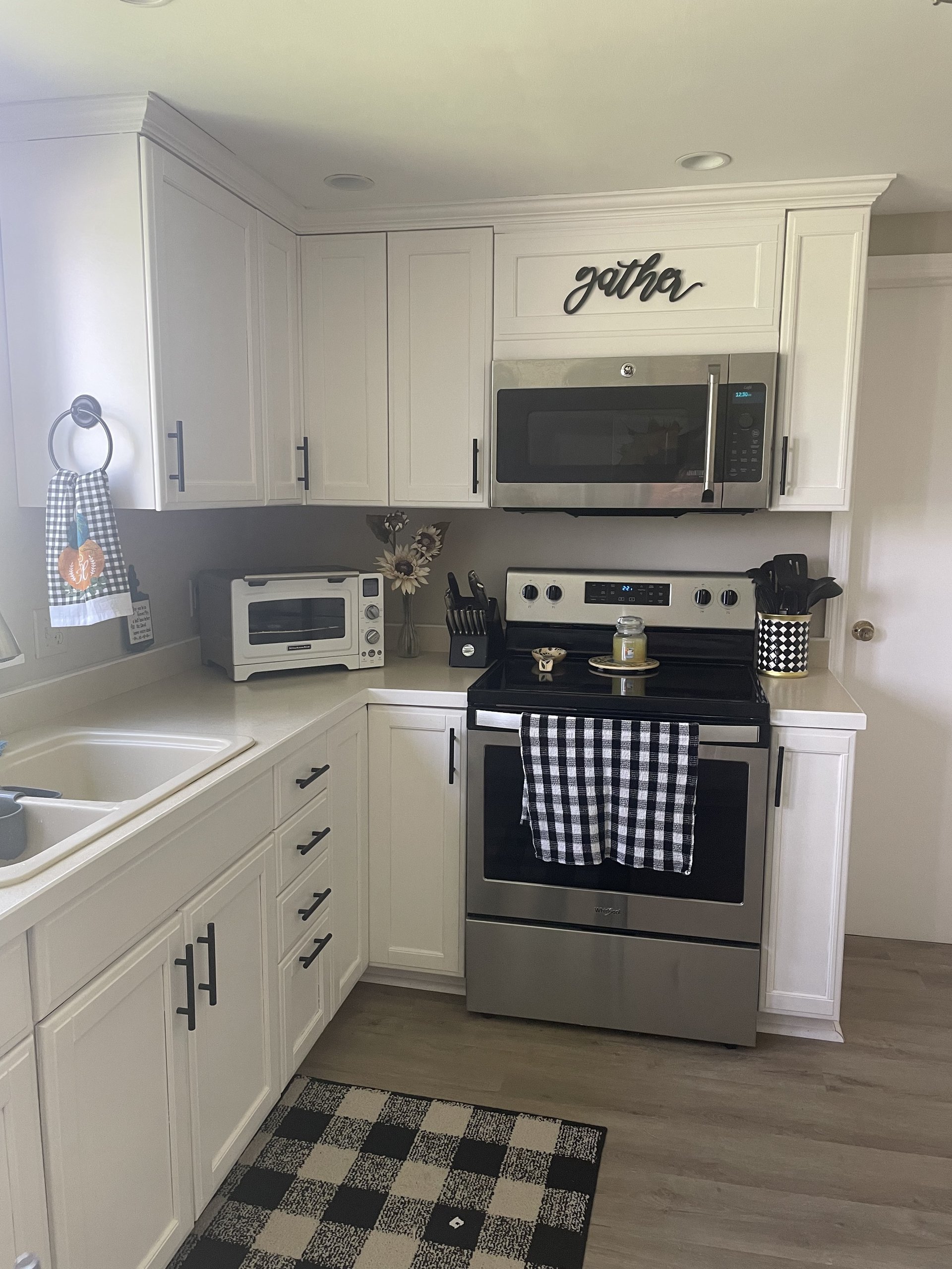 White cabinetry surrounds the stainless range and microwave, gather sign above