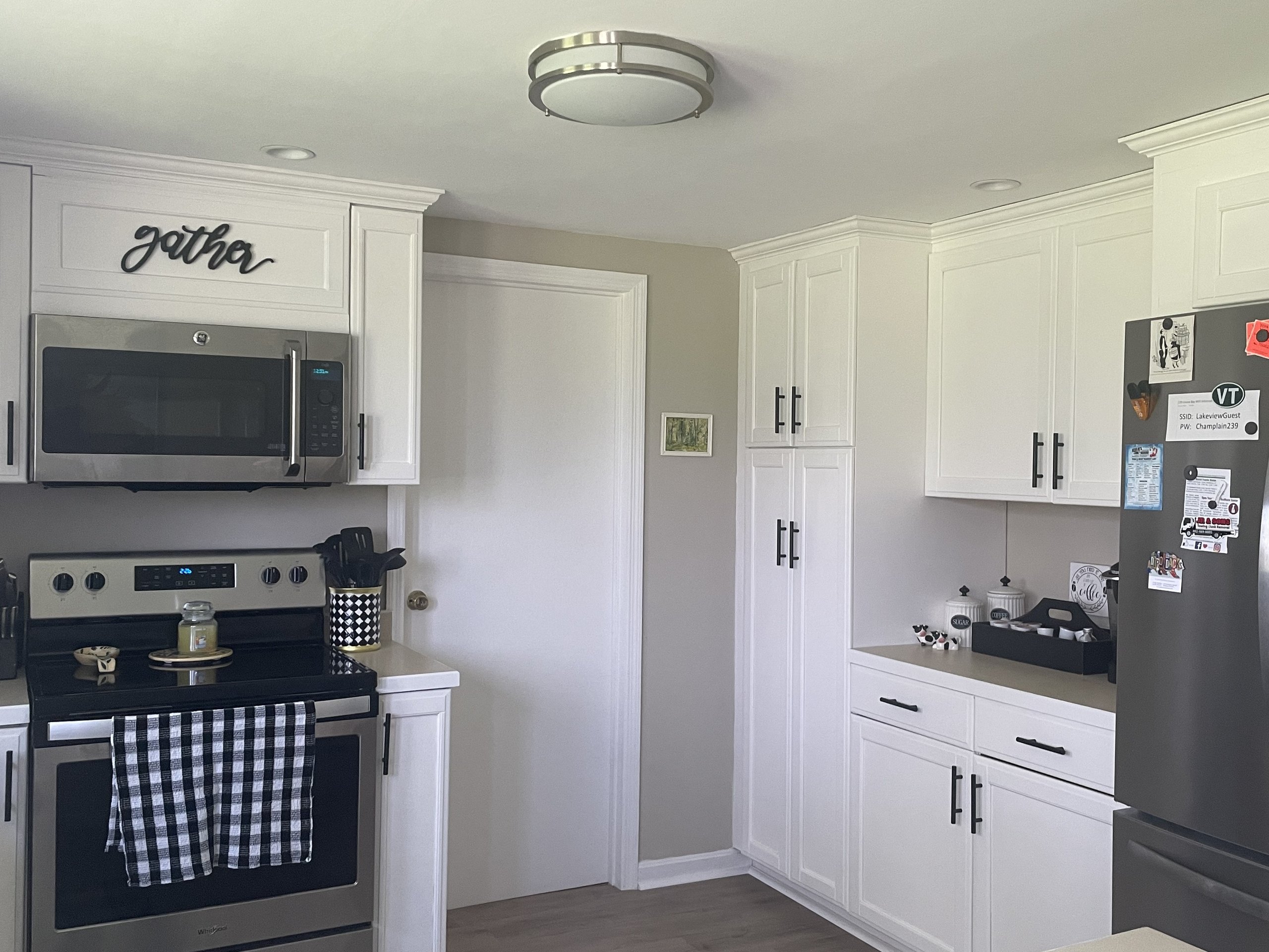 Kitchen corner showing pantry cabinets, refrigerator, and overhead flush-mount lighting
