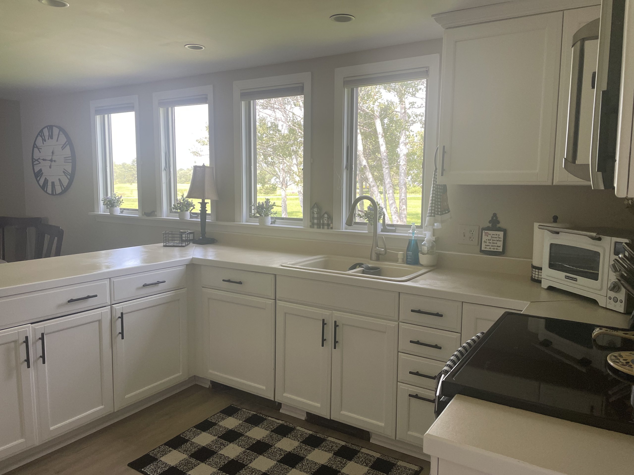 Sink and countertop stretch beneath four windows framing the green yard