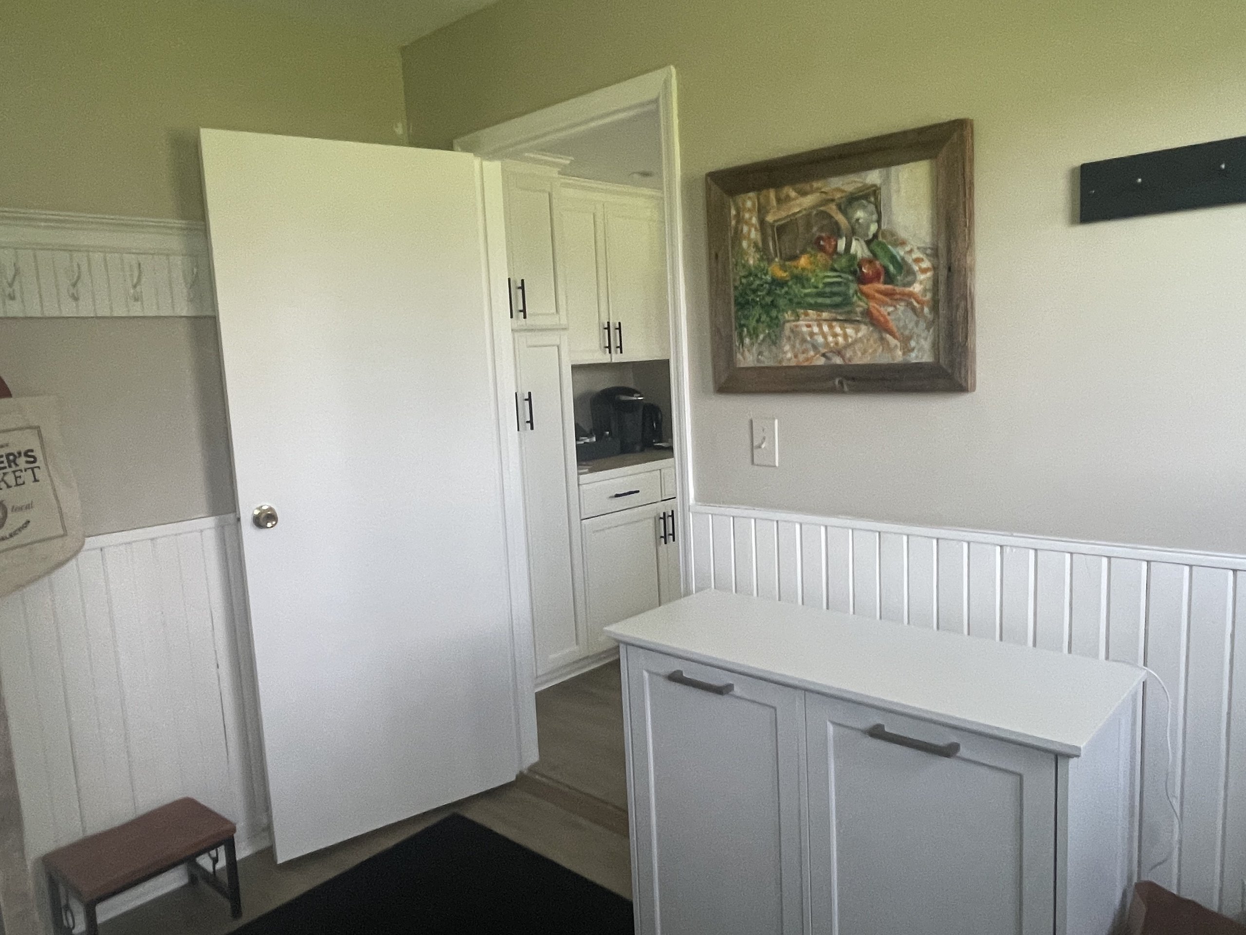 Mudroom nook with wall hooks, a bench, and a still-life painting