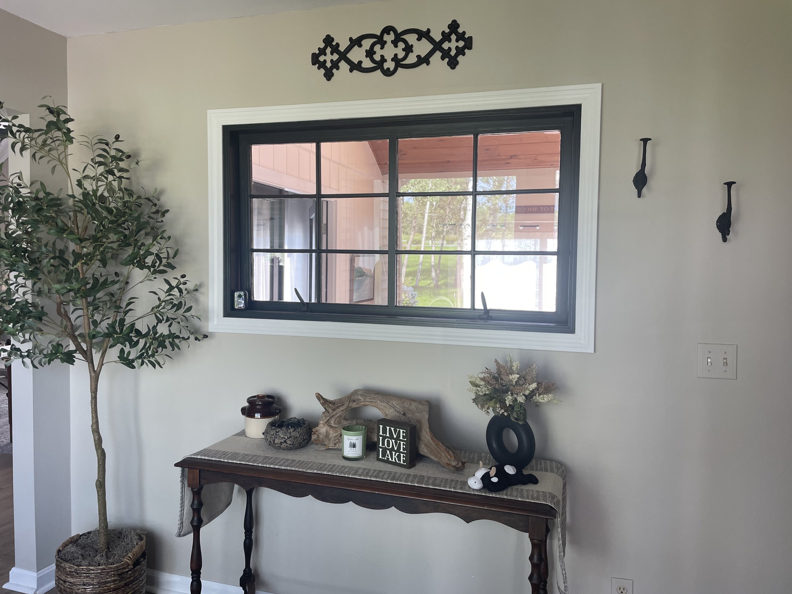 Entry console table with driftwood decor beneath a large picture window