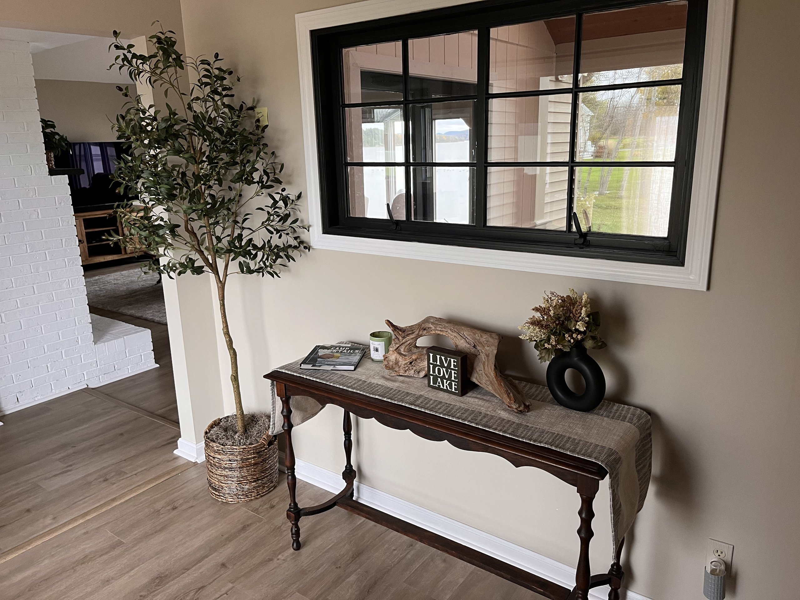 Console table vignette opening toward the living room's white brick fireplace