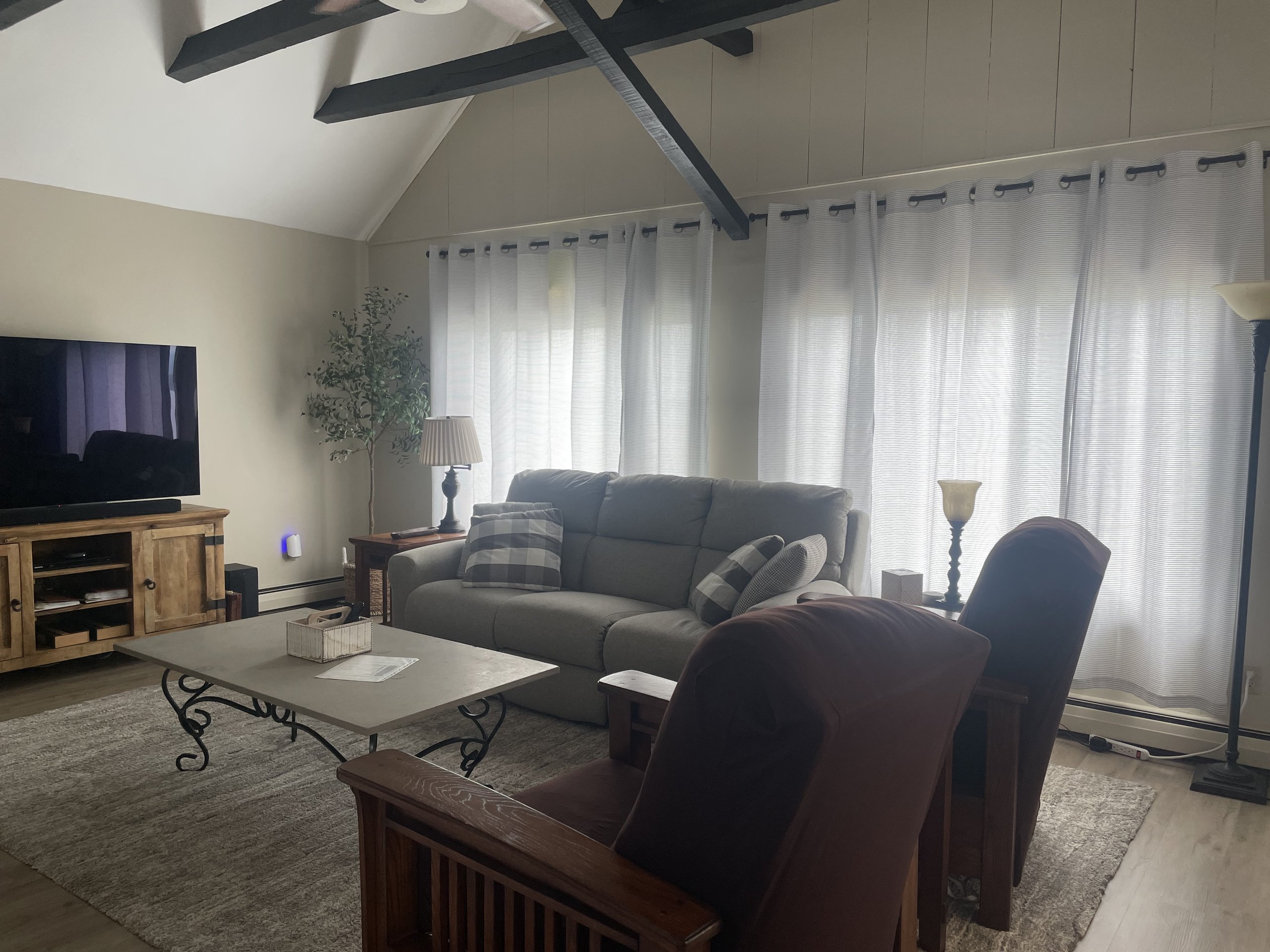 Vaulted, beamed ceiling rises above the family room's sofa and armchairs