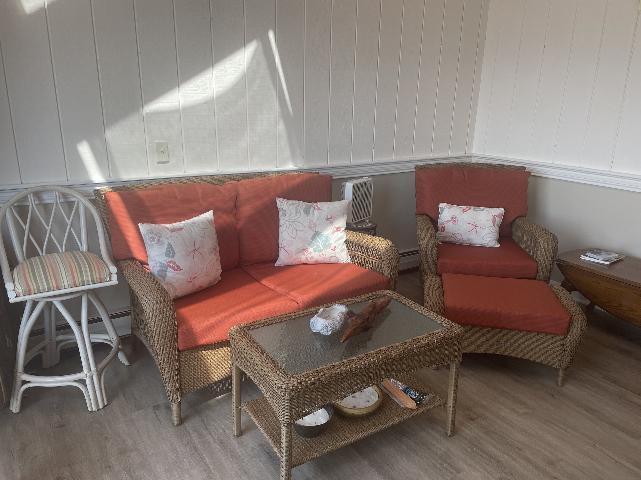 Screened porch seating with rust wicker chairs and floral accent pillows