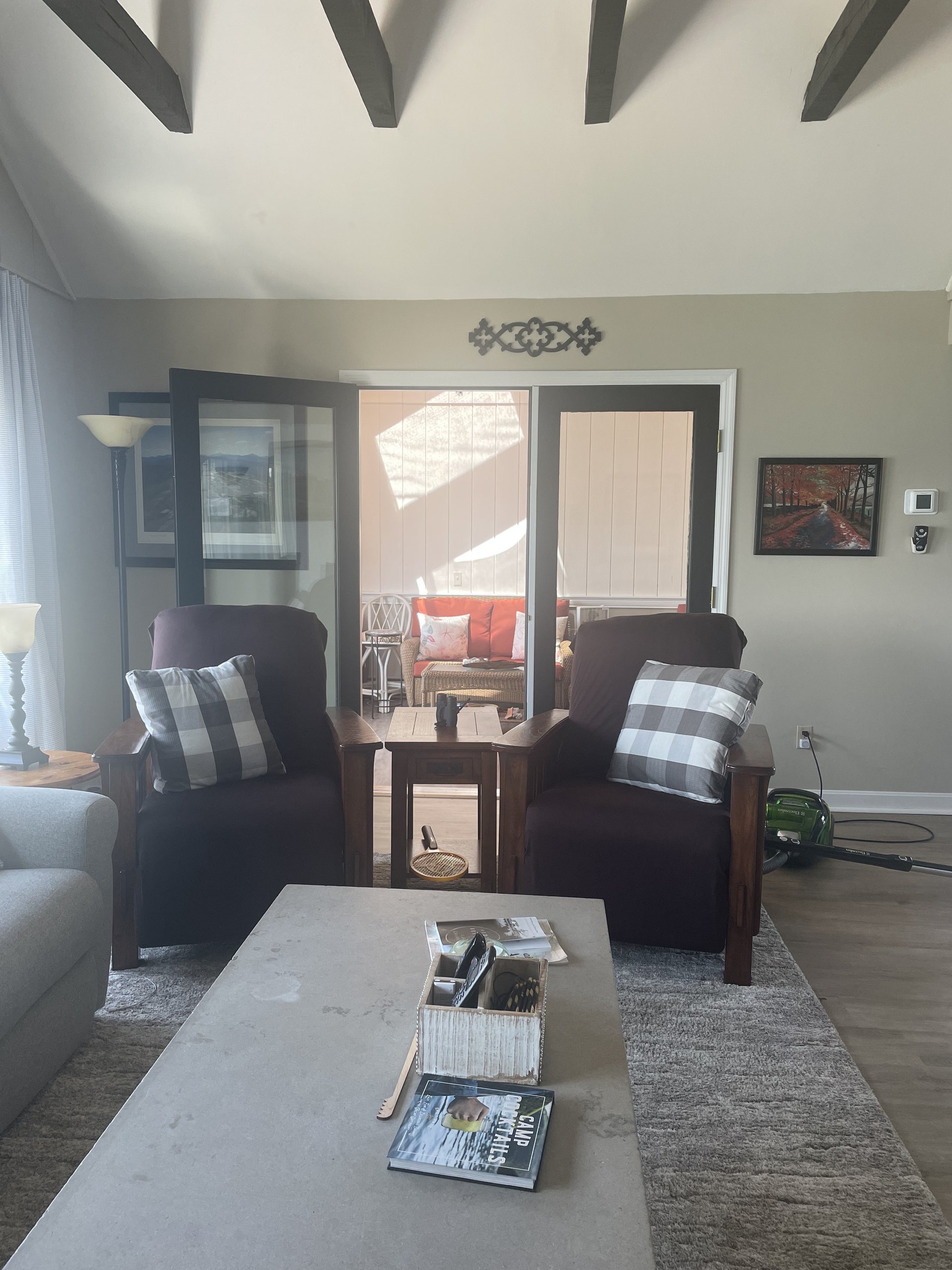 Pair of leather armchairs with buffalo-check pillows near the porch doors