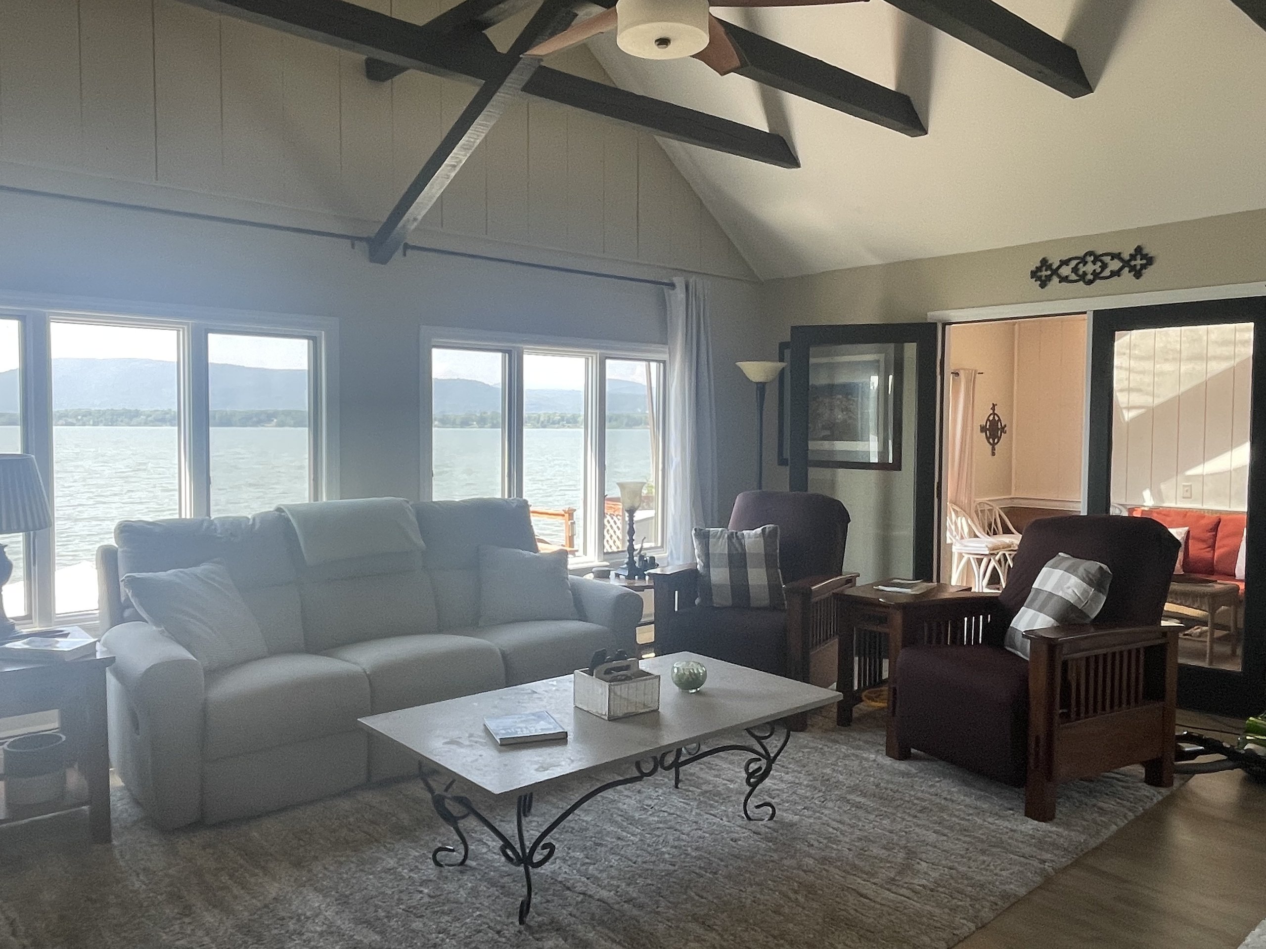 Living room sofas face floor-to-ceiling windows with sweeping Lake Champlain views