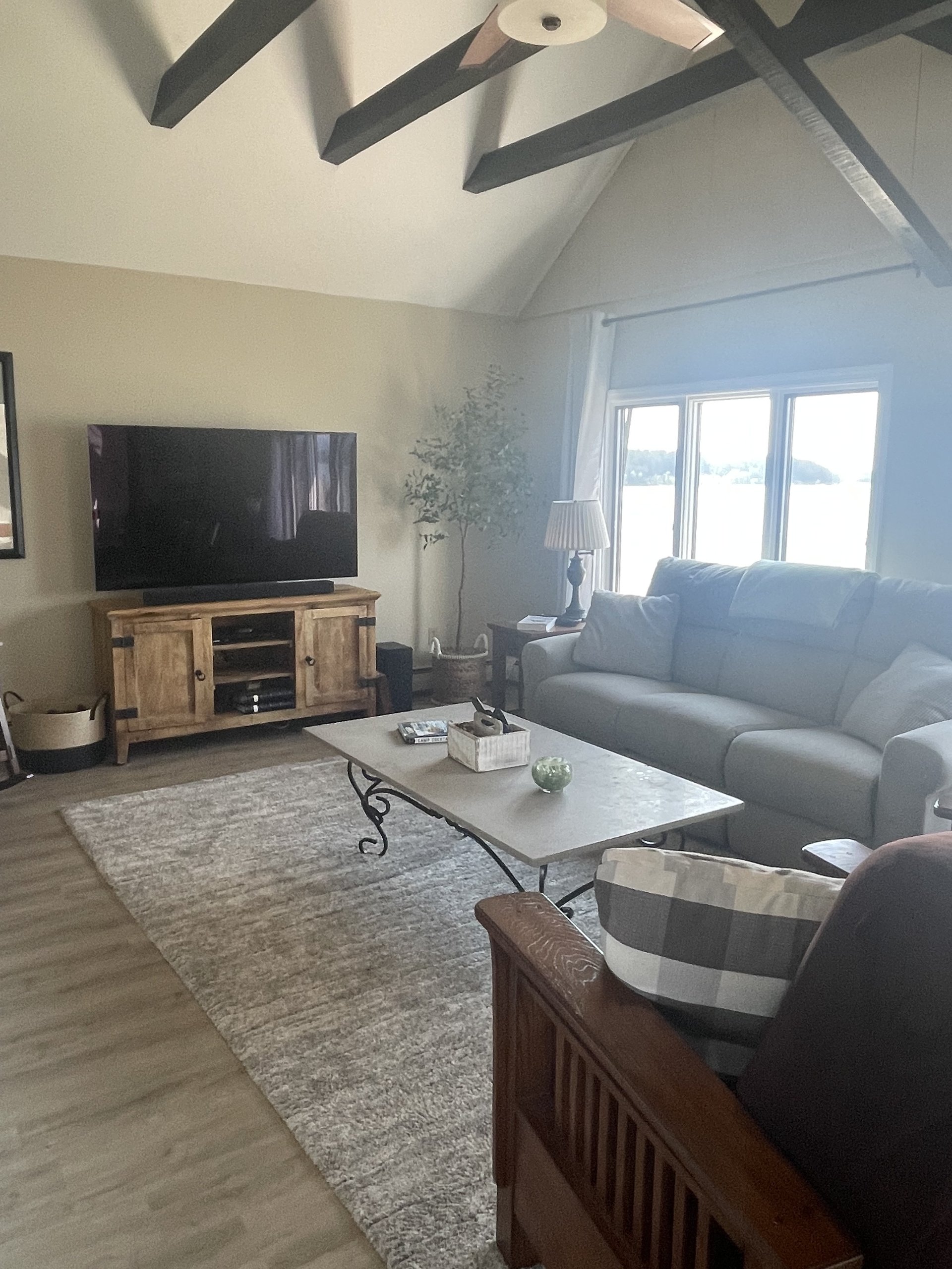 Wood media console and TV beside a potted faux olive tree