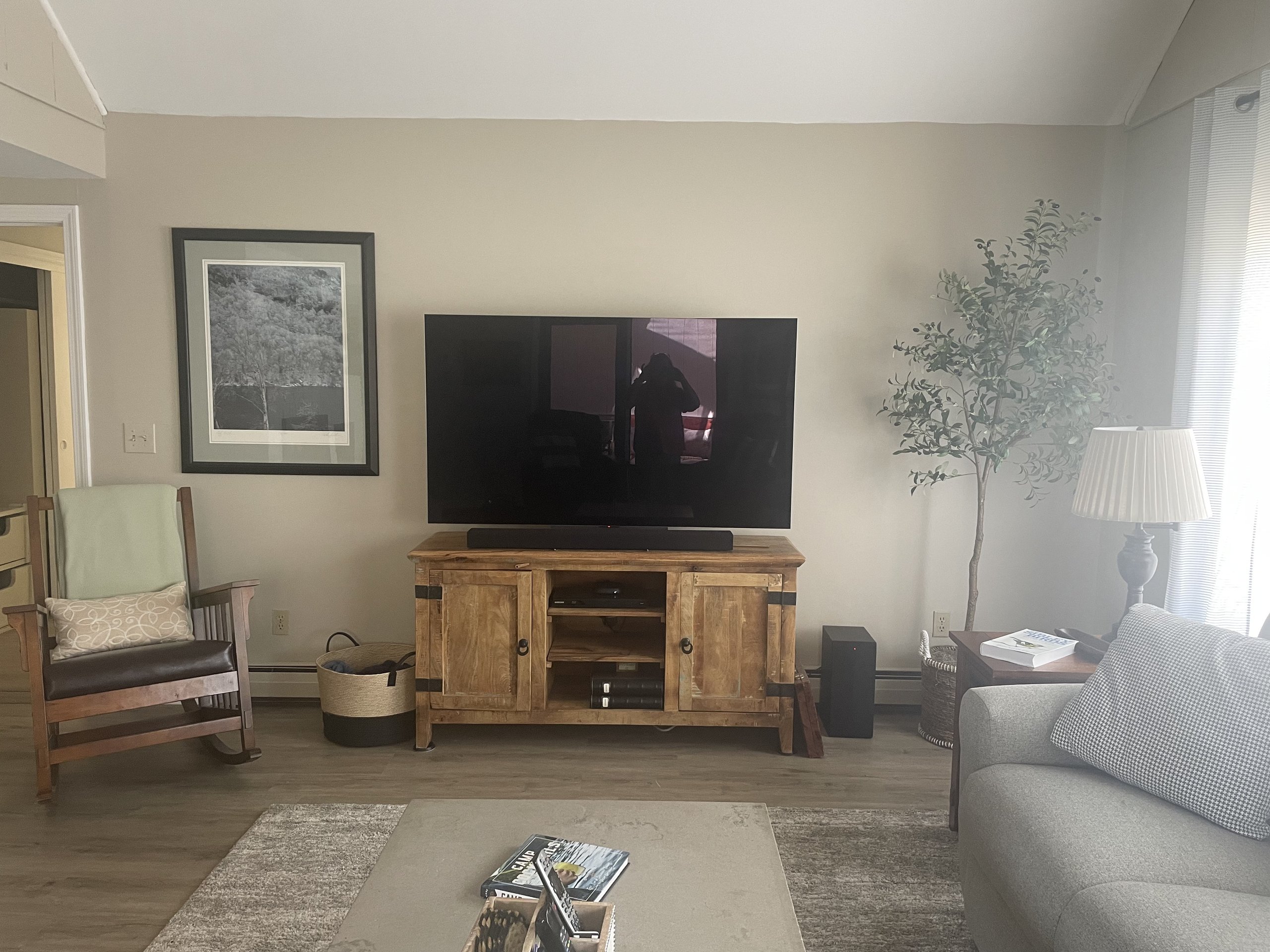 Rustic wood TV console flanked by a rocking chair and armchair