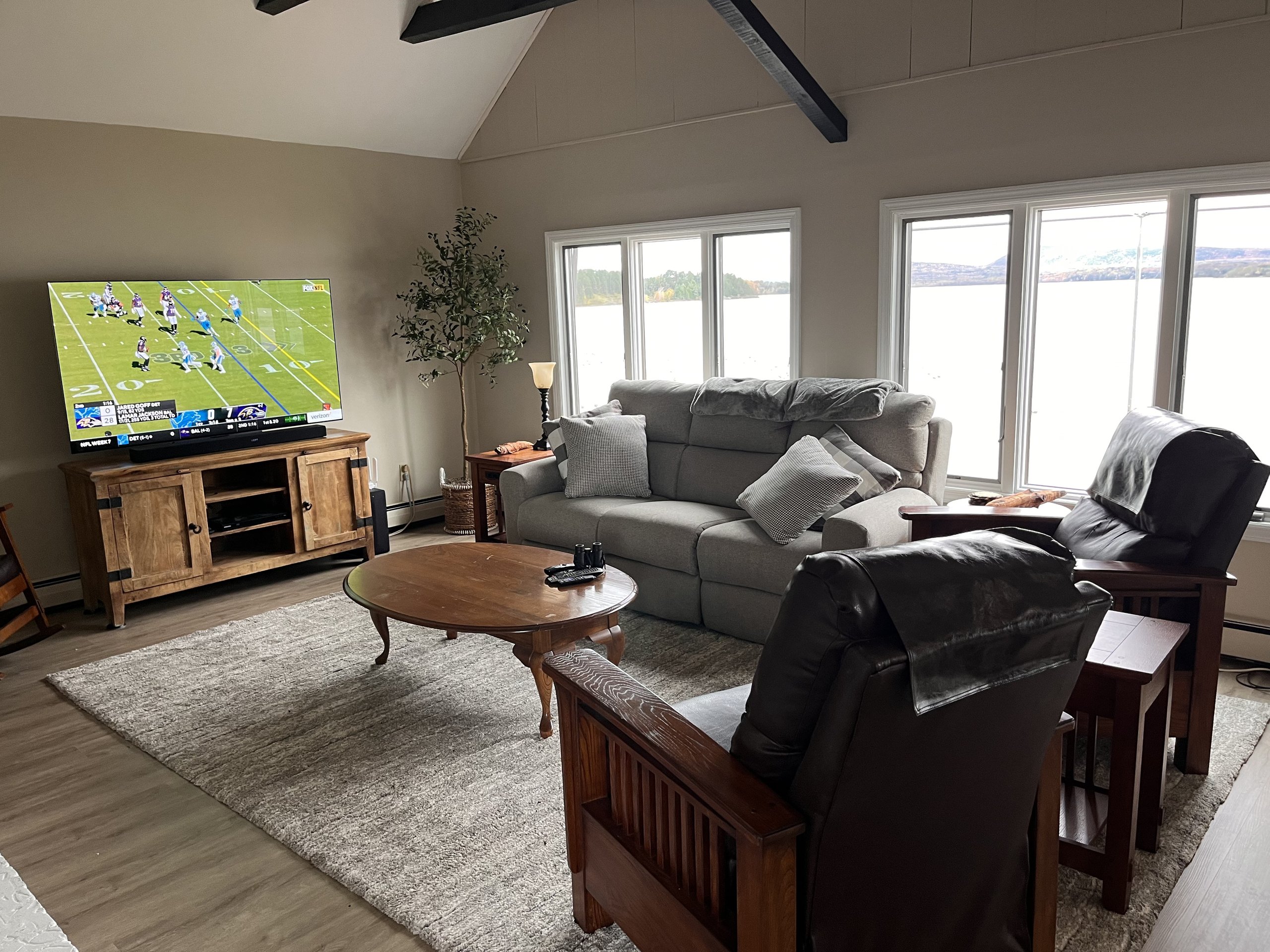 Sofa and recliners arranged for TV watching with lake views behind