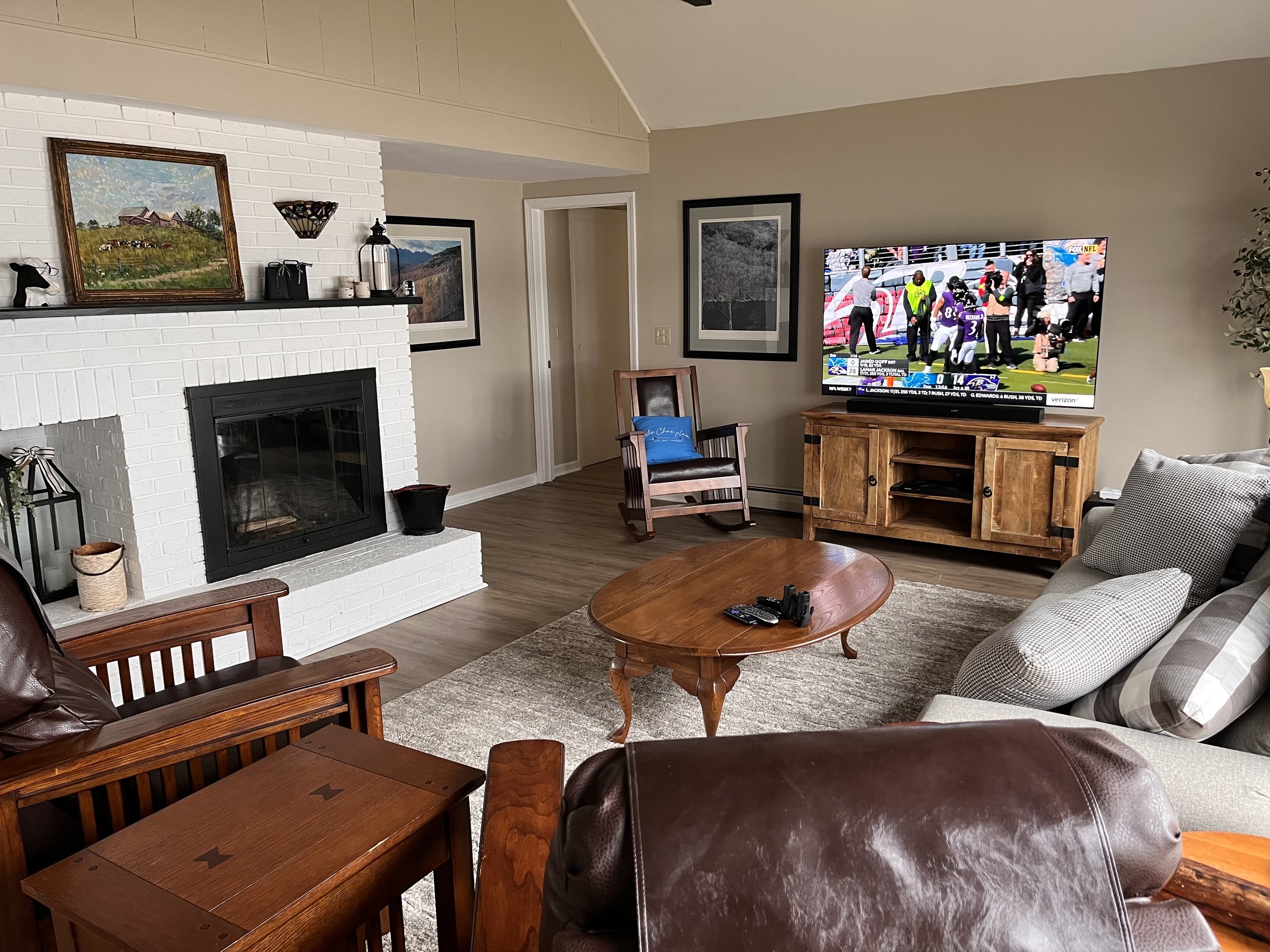 White-painted brick fireplace stands beside the TV and wood console