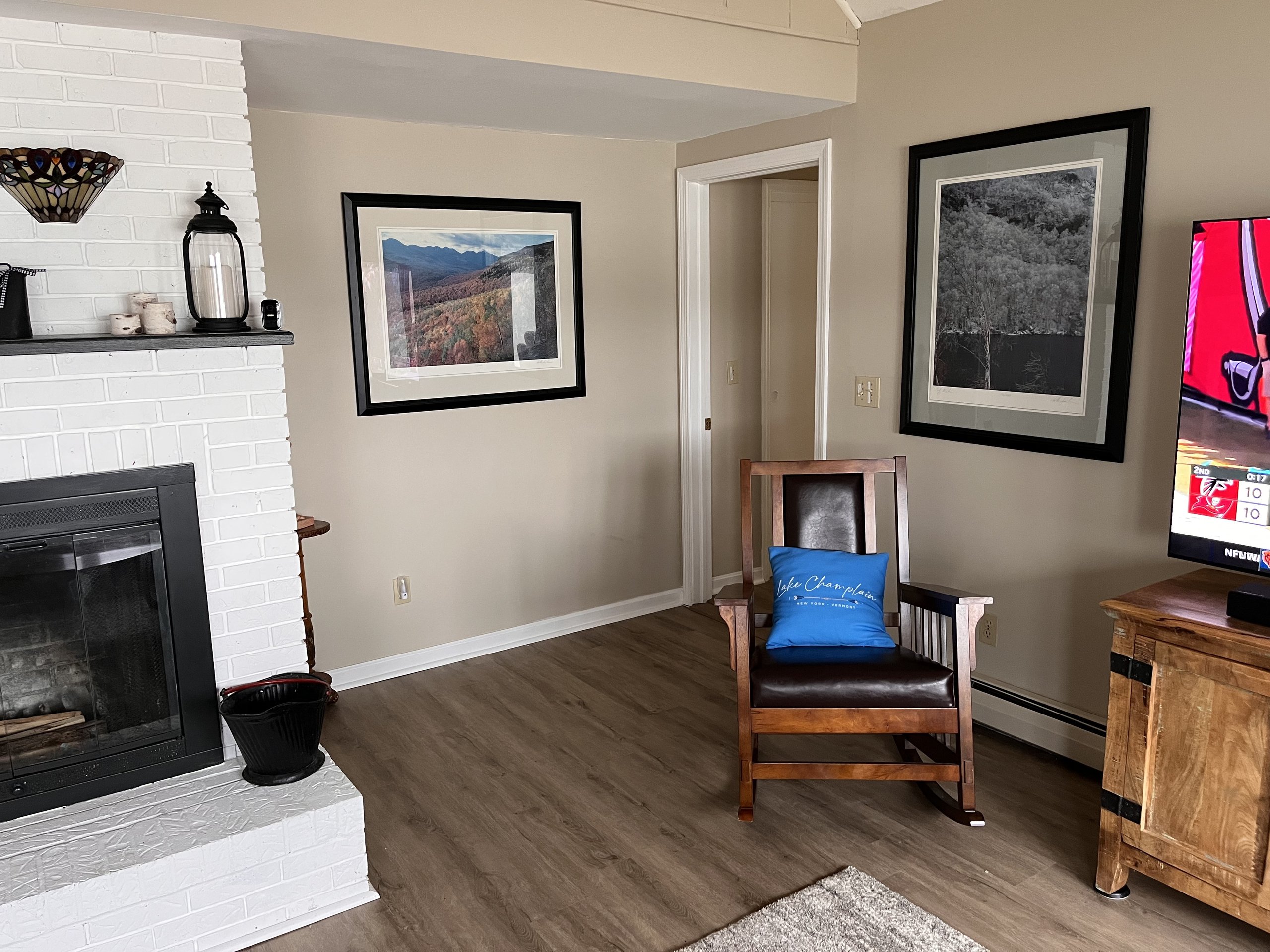 Framed Vermont landscape prints hang beside a leather-seated rocking chair