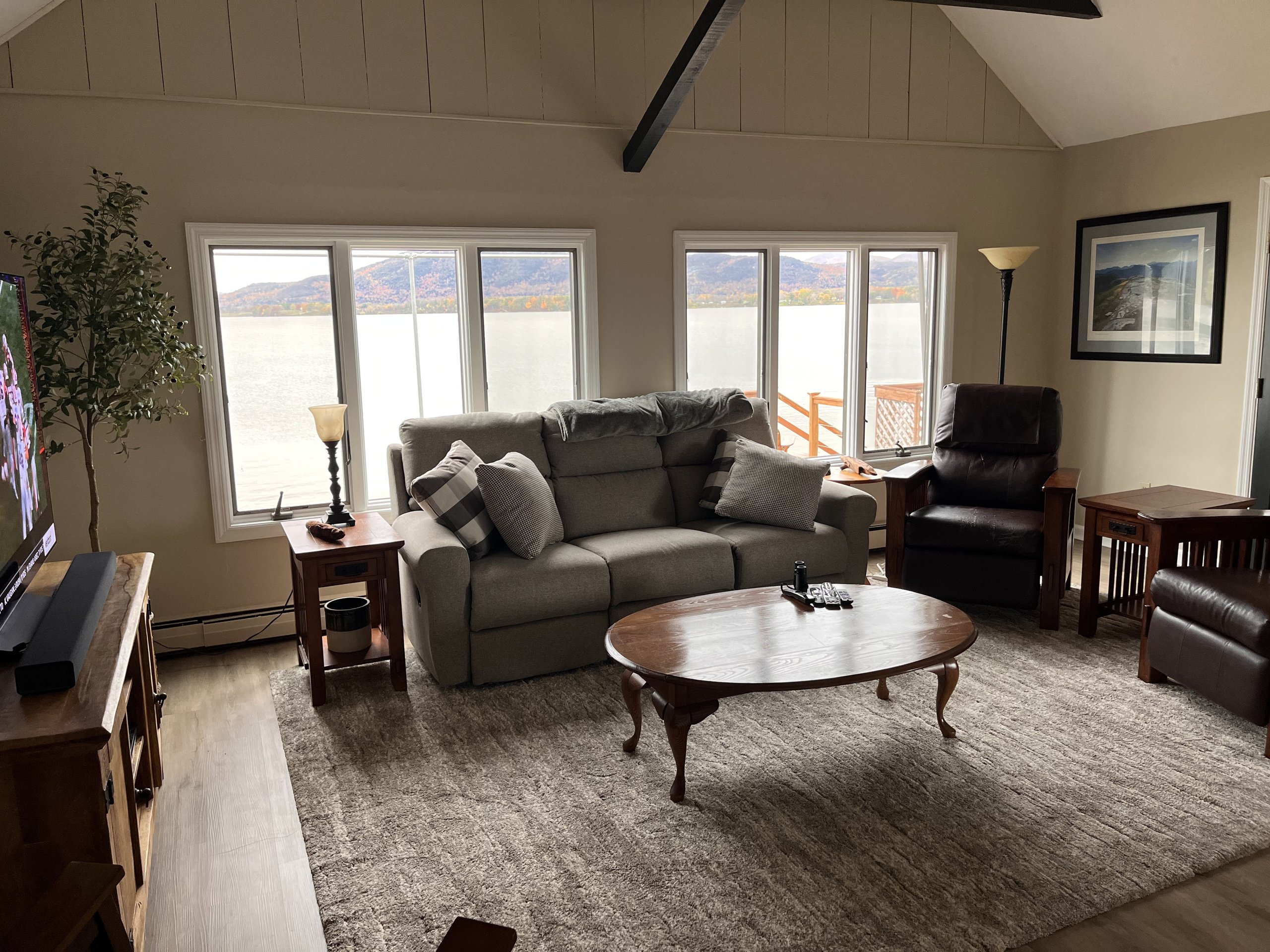 Gray sofa and leather recliner overlook the lake through large windows
