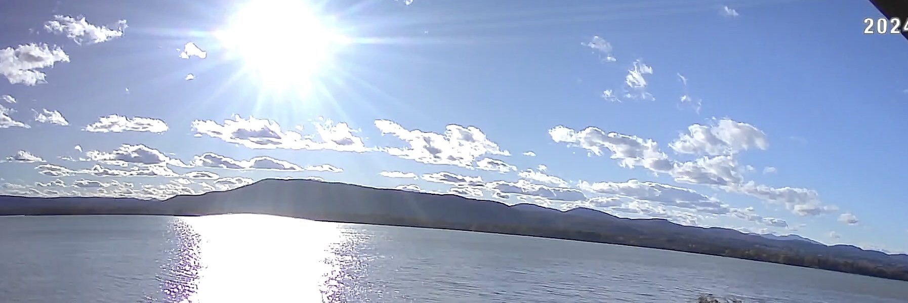 Bright sunny panorama of the lake with sunlight sparkling on the water