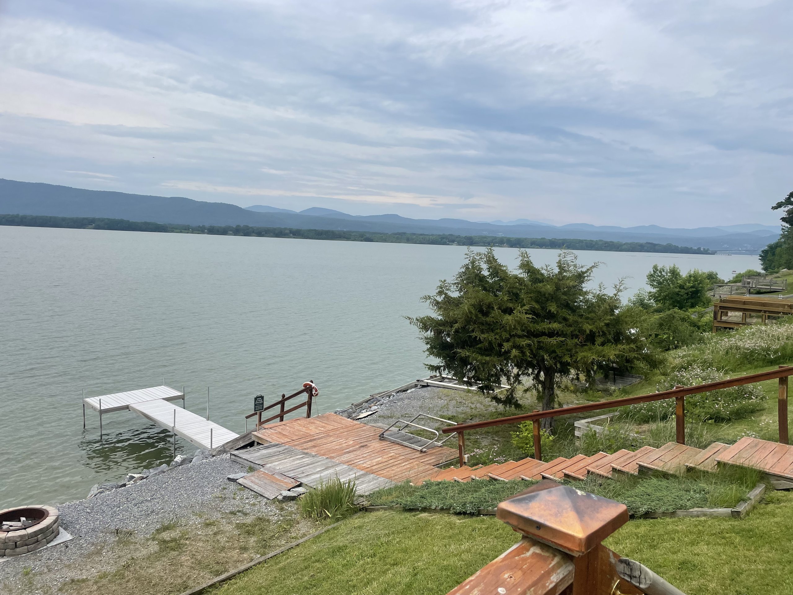 Wooden stairs descend past a dock toward the misty mountains beyond
