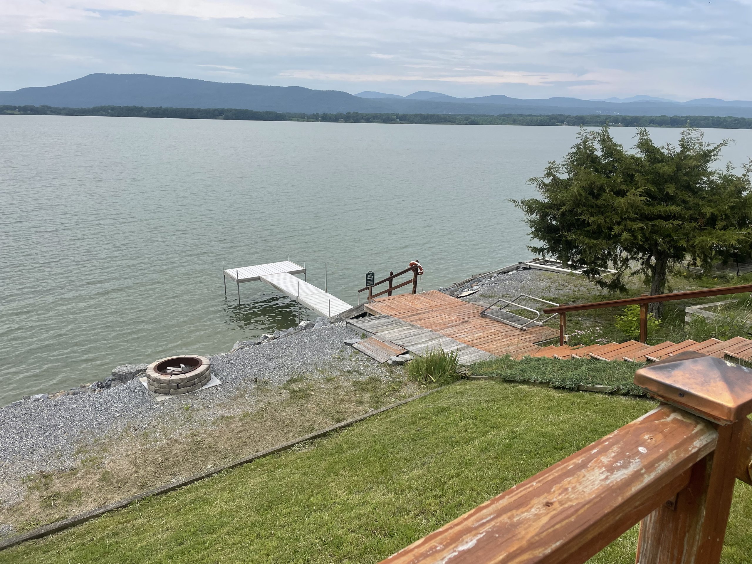 A fire pit and dock sit along the rocky shoreline under a gray sky