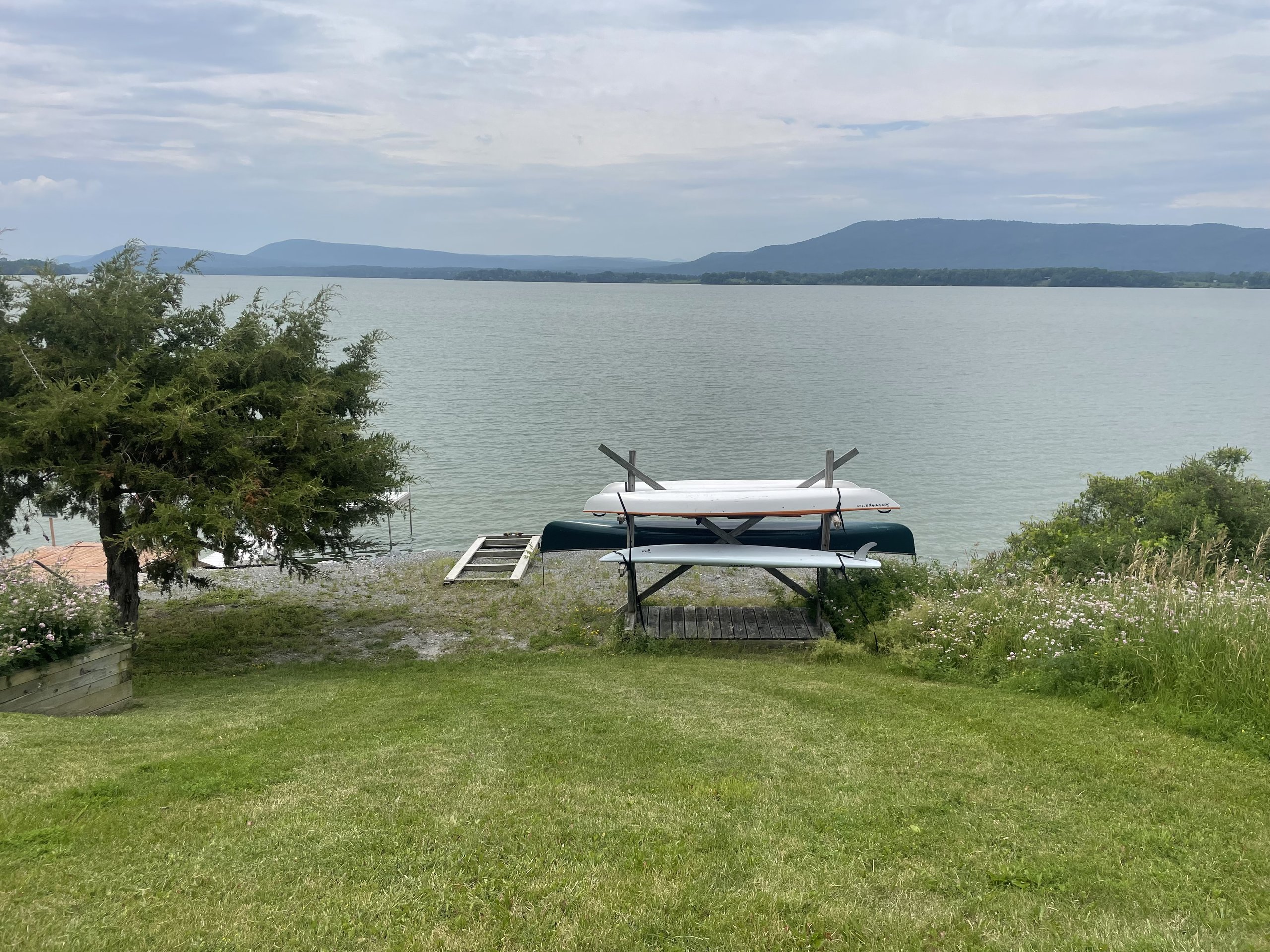 Kayaks and a paddleboard stand ready on their rack by the shoreline