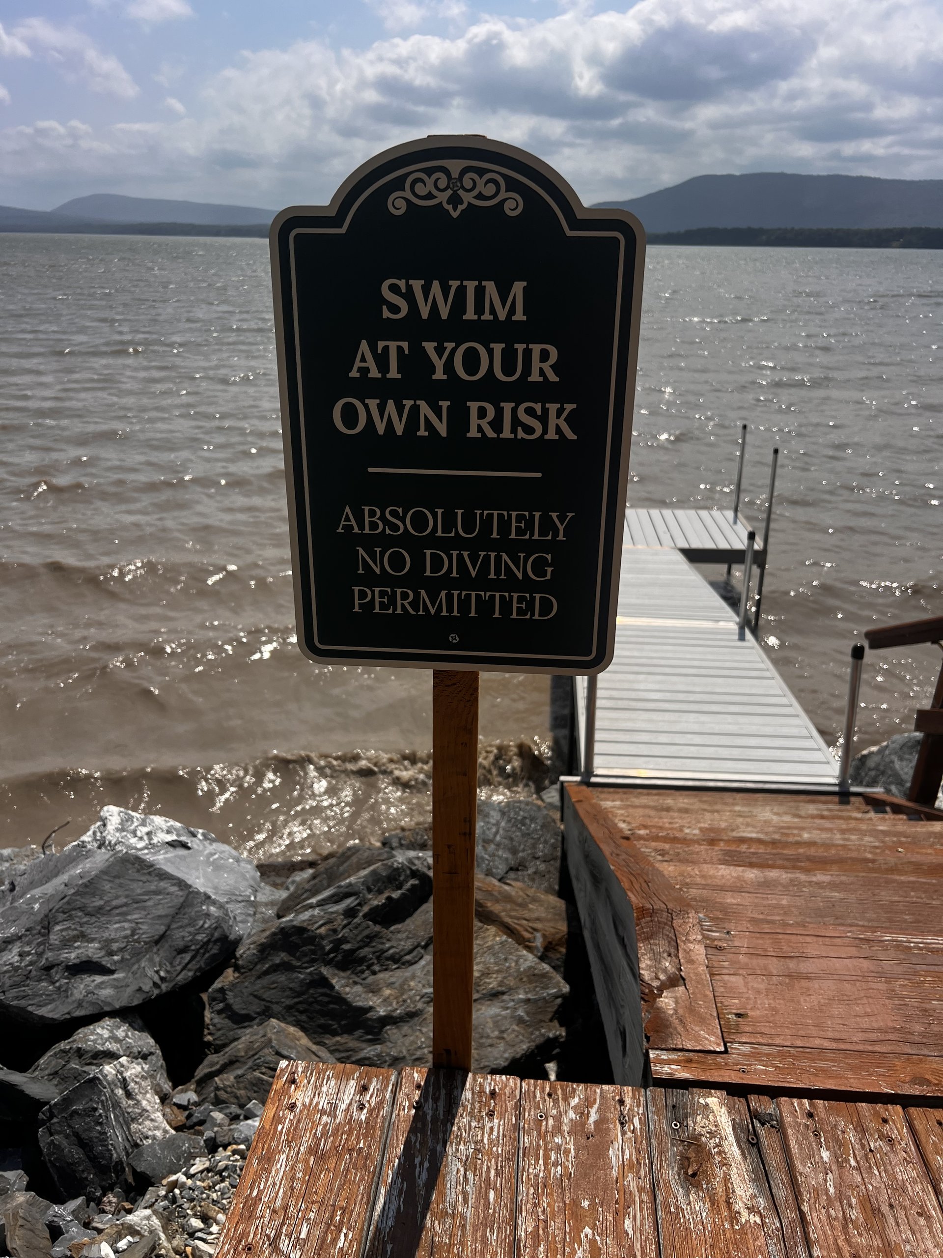 A swim-at-your-own-risk sign marks the path to the private dock