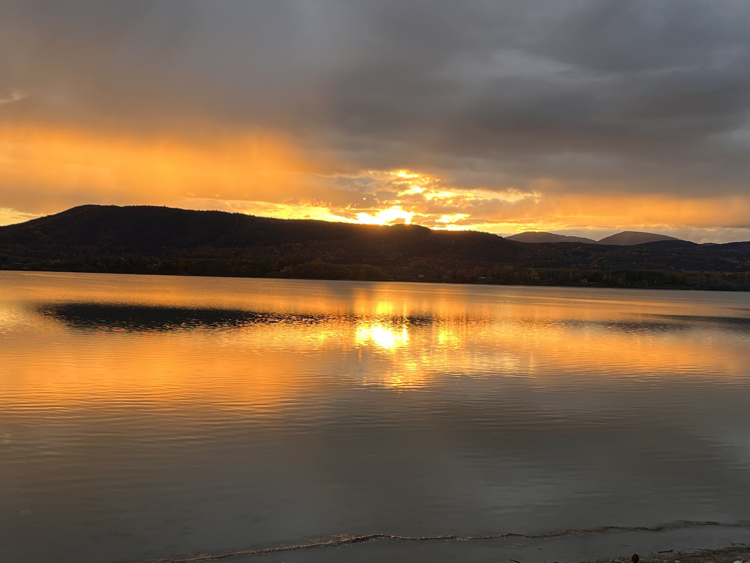 Molten orange sunset reflects in a long shimmering path across calm water