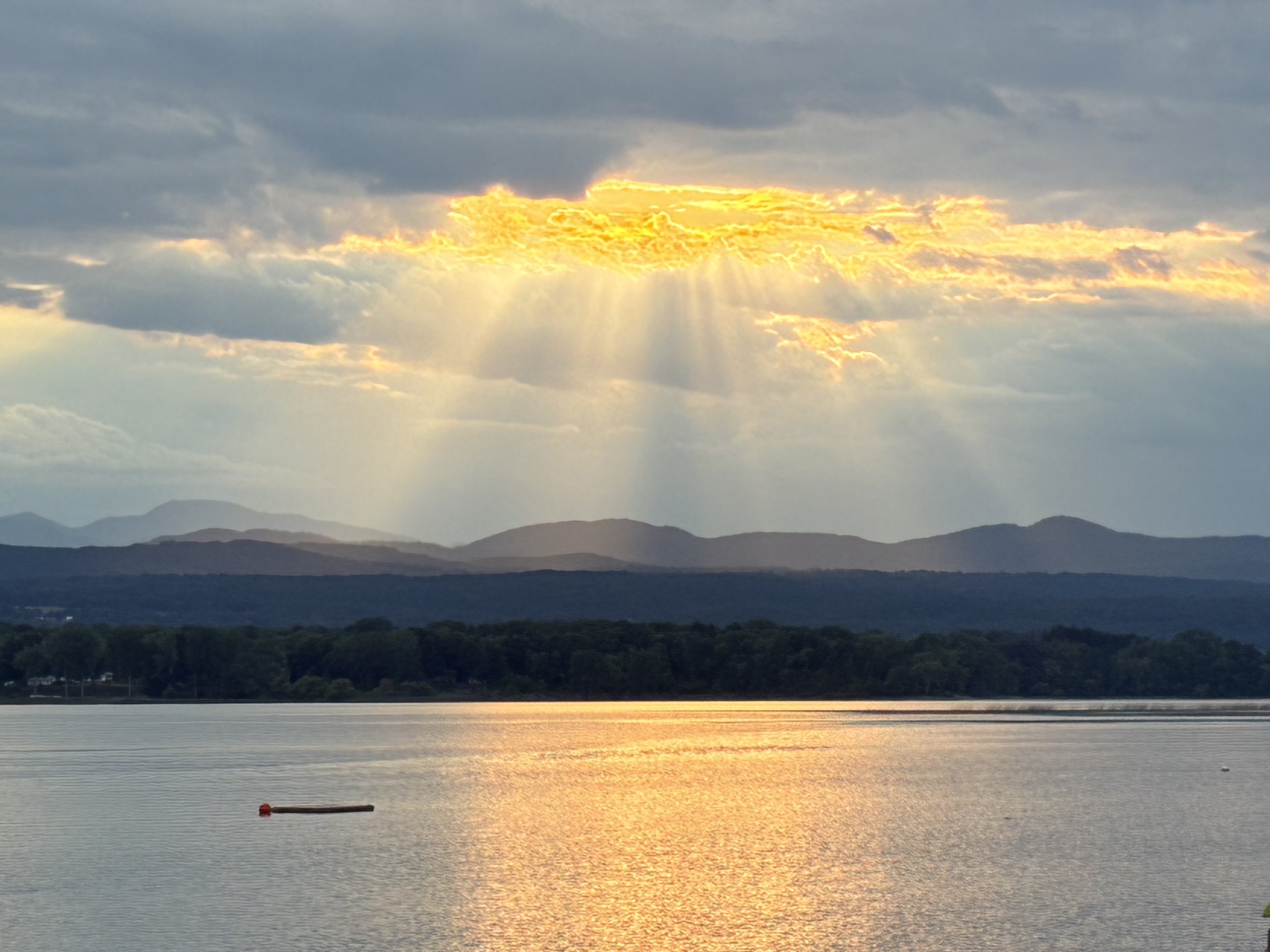 Rays of sunlight fan out through clouds over the mountains at dusk