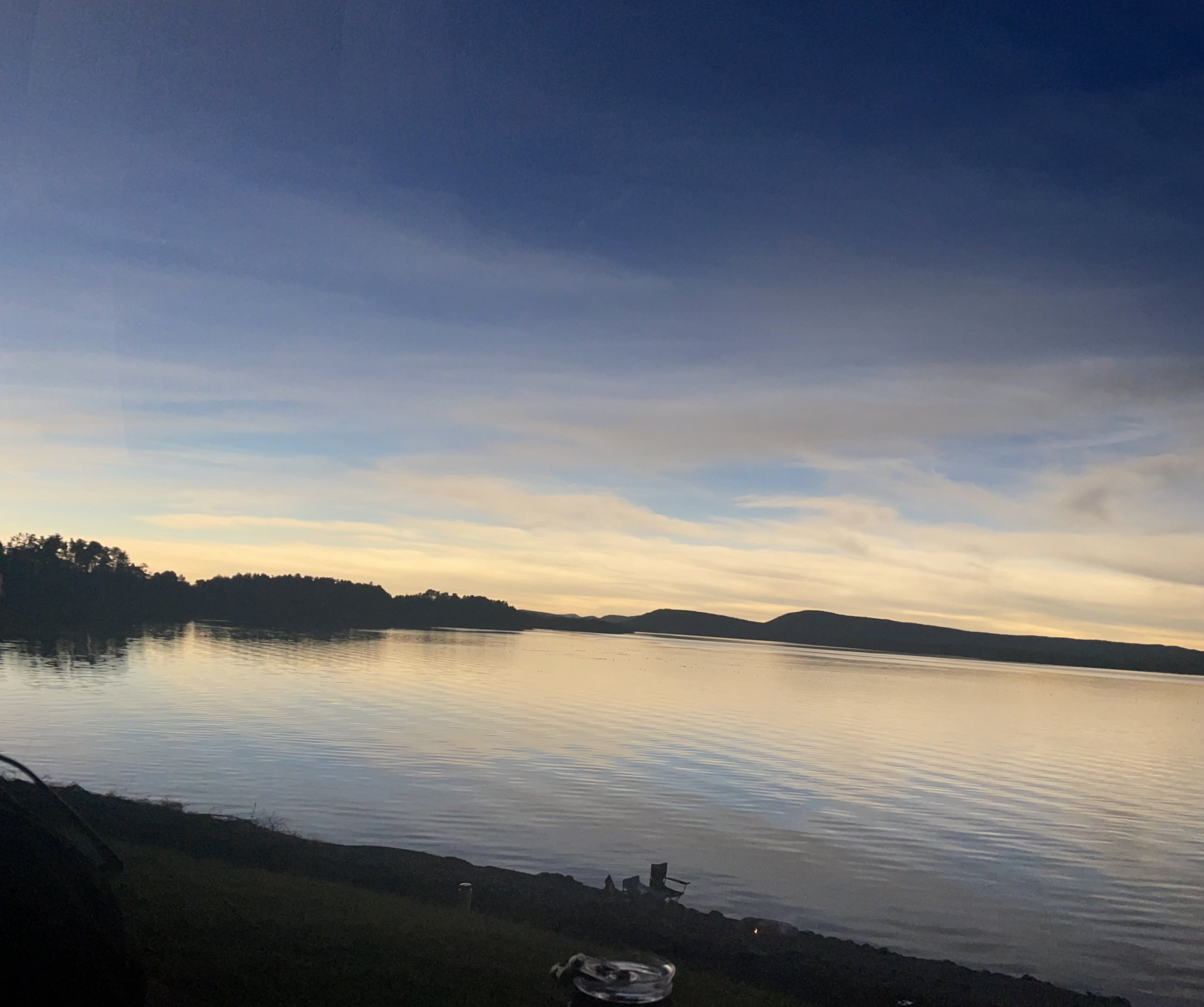 Soft dusk colors settle over the calm lake and distant hills