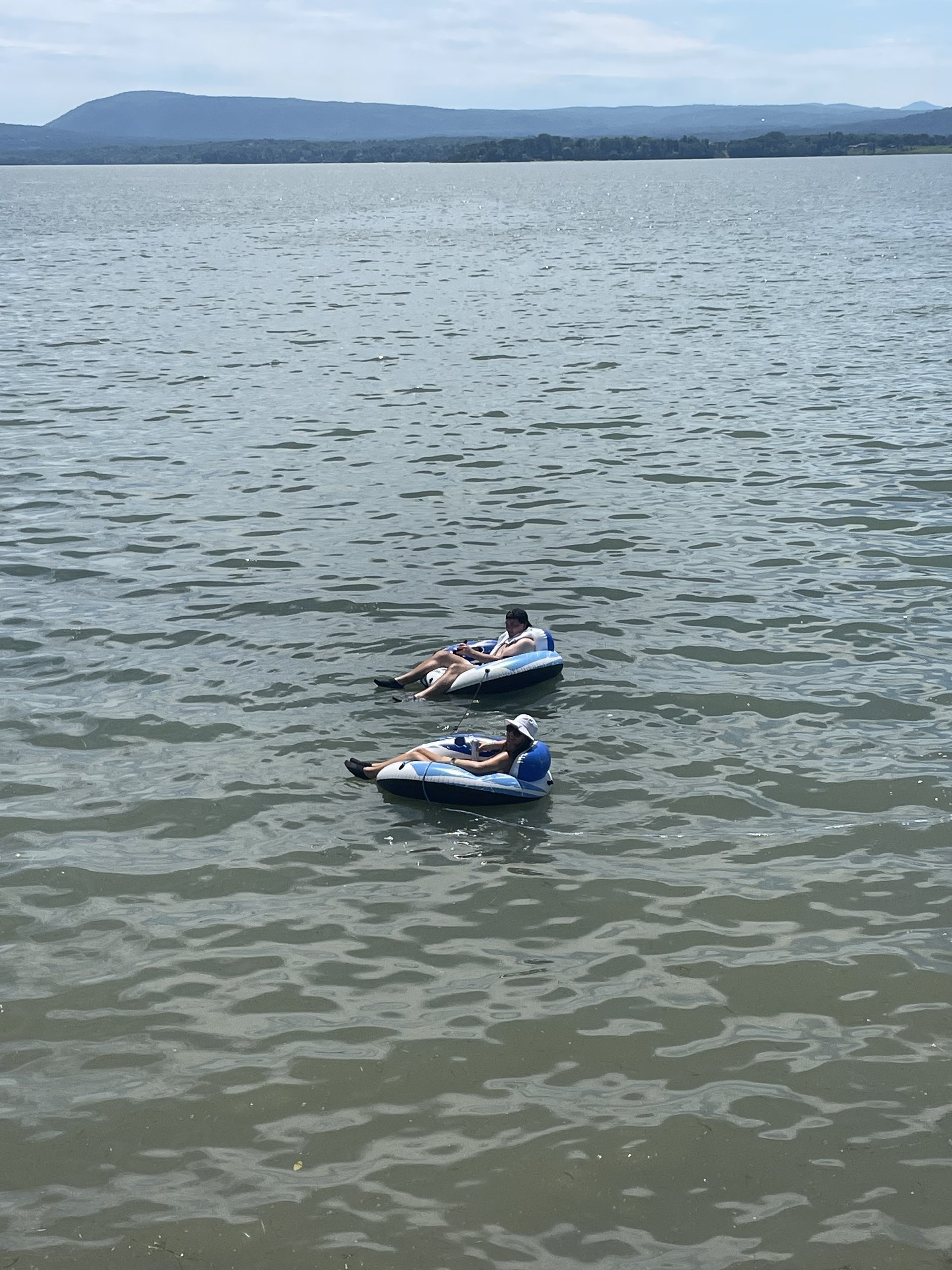 Guests relax on inflatable tubes floating on the lake on a summer day