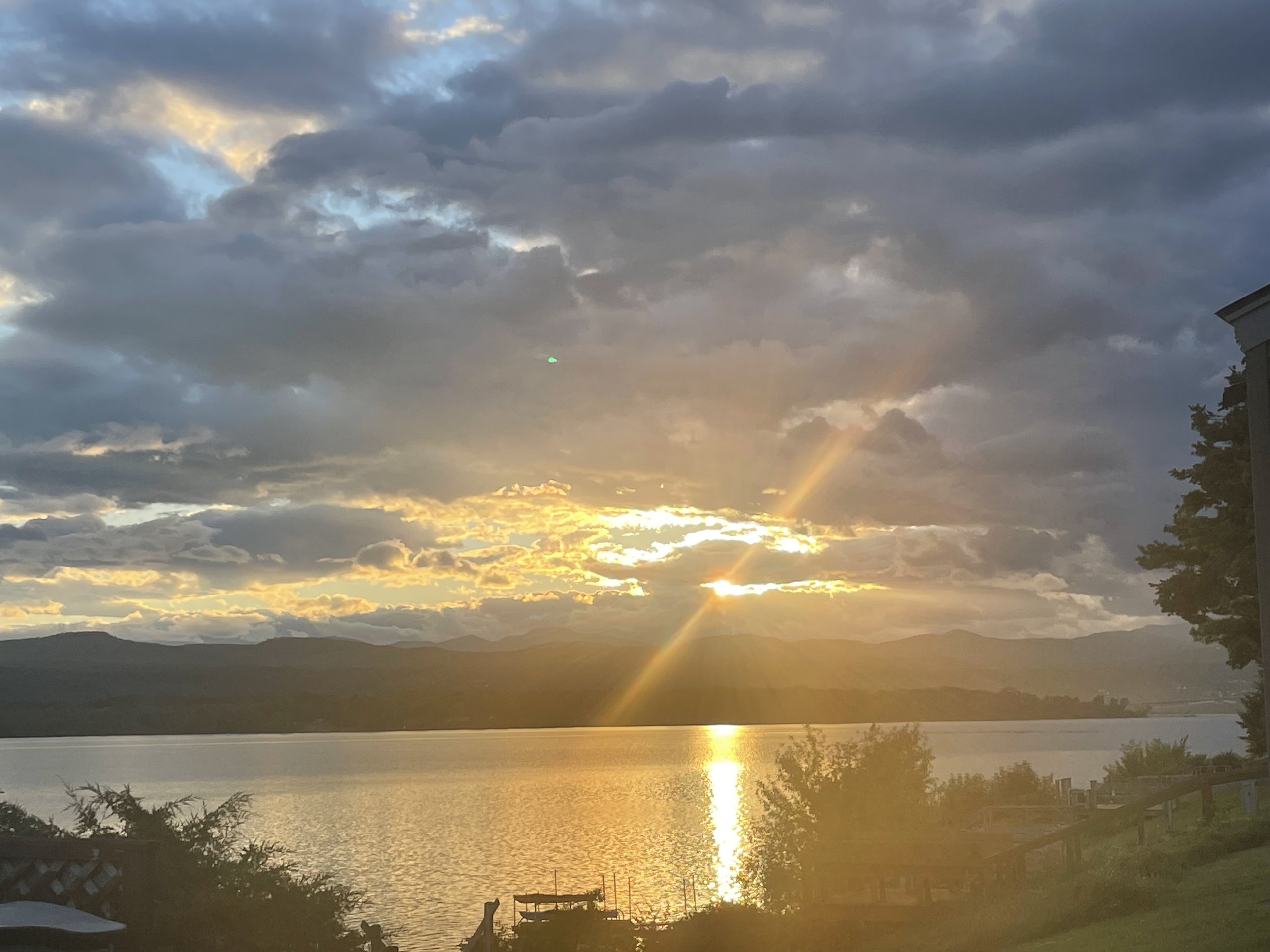 Sunbeam pierces the clouds above docked boats during a colorful evening sunset