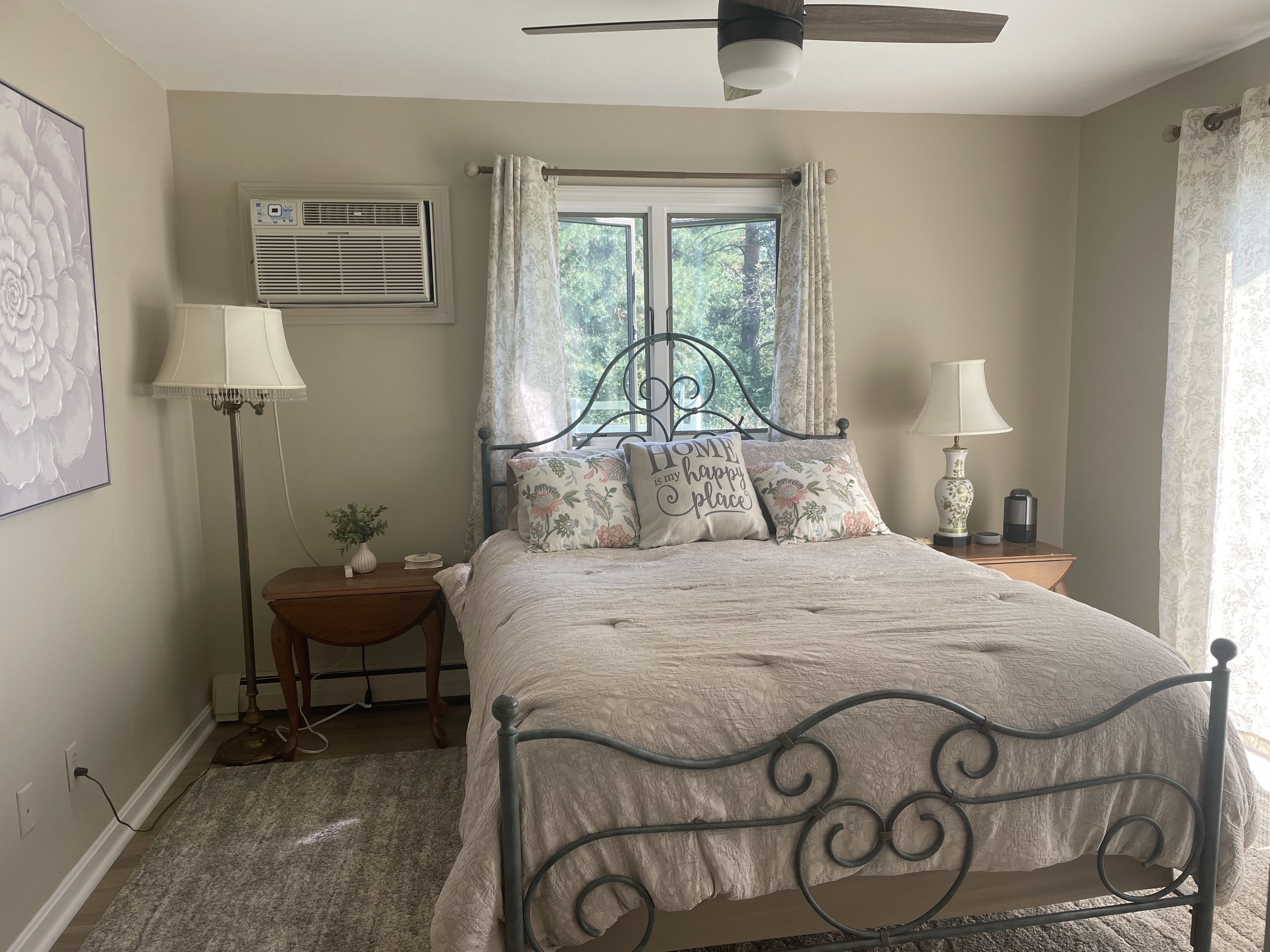 Wrought-iron bed beneath a ceiling fan, framed by a wooded window