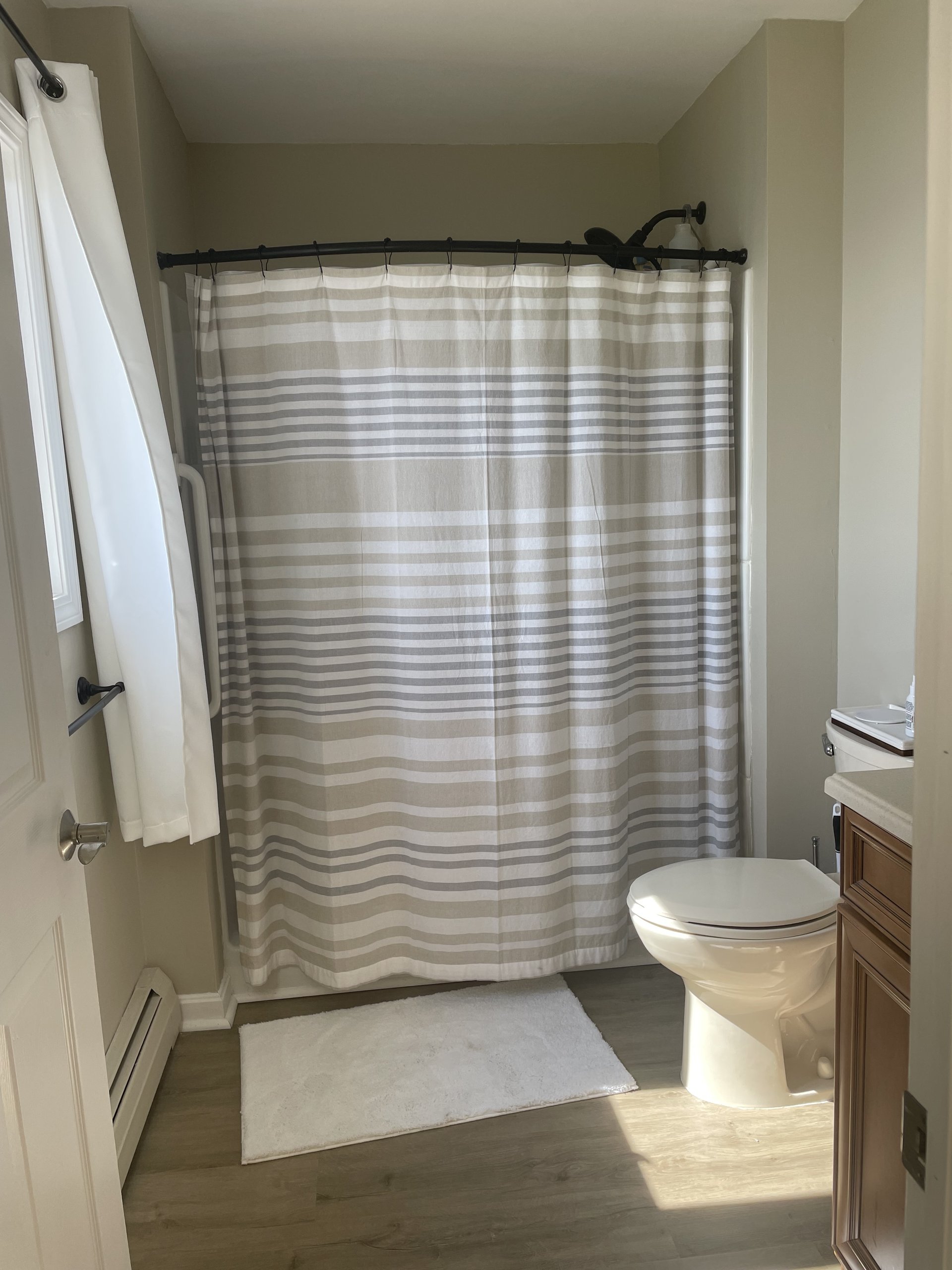 Bathroom shower area with striped curtain and a plush bath mat