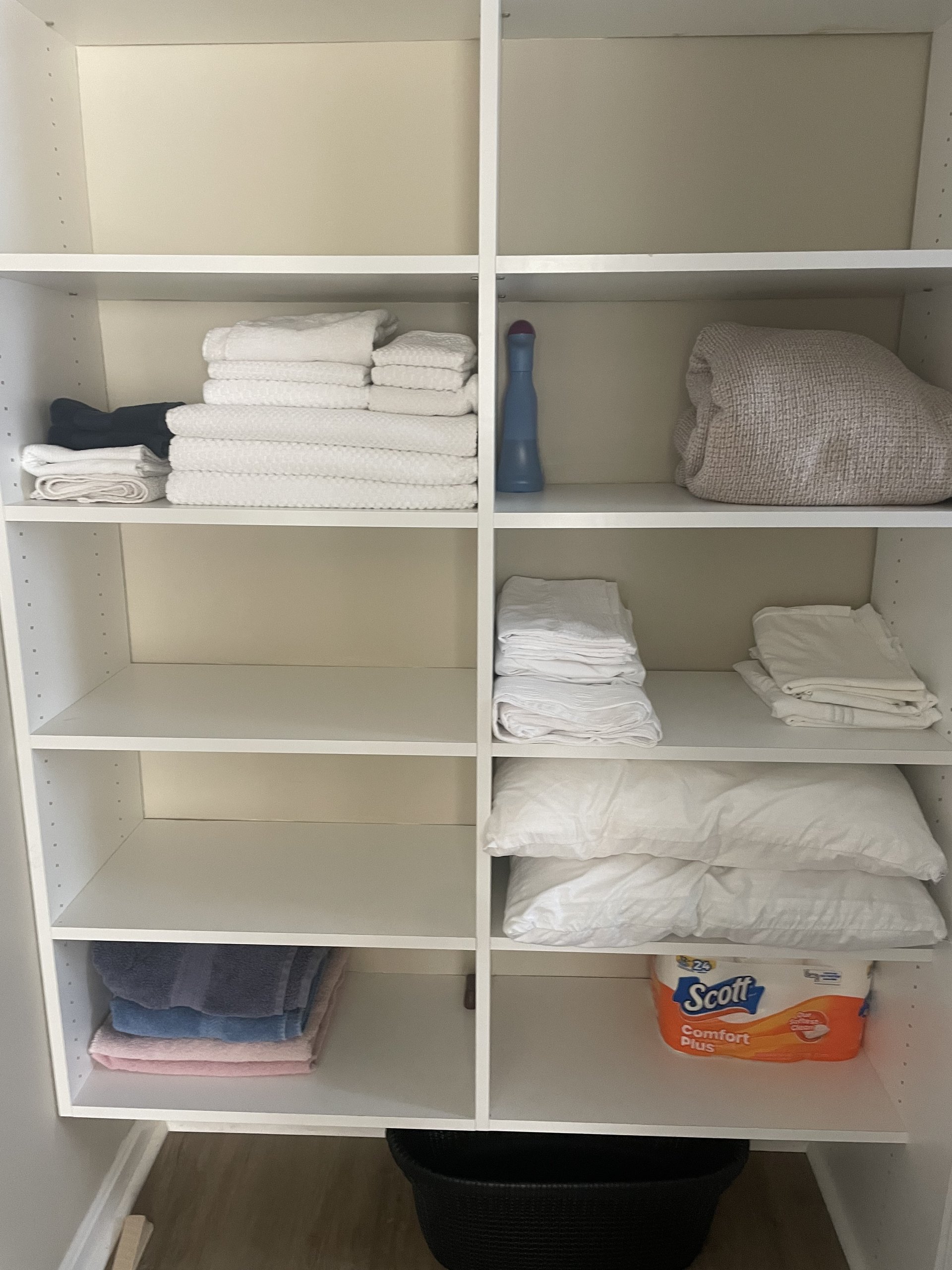 Linen closet stocked with folded towels, sheets, pillows, and paper goods