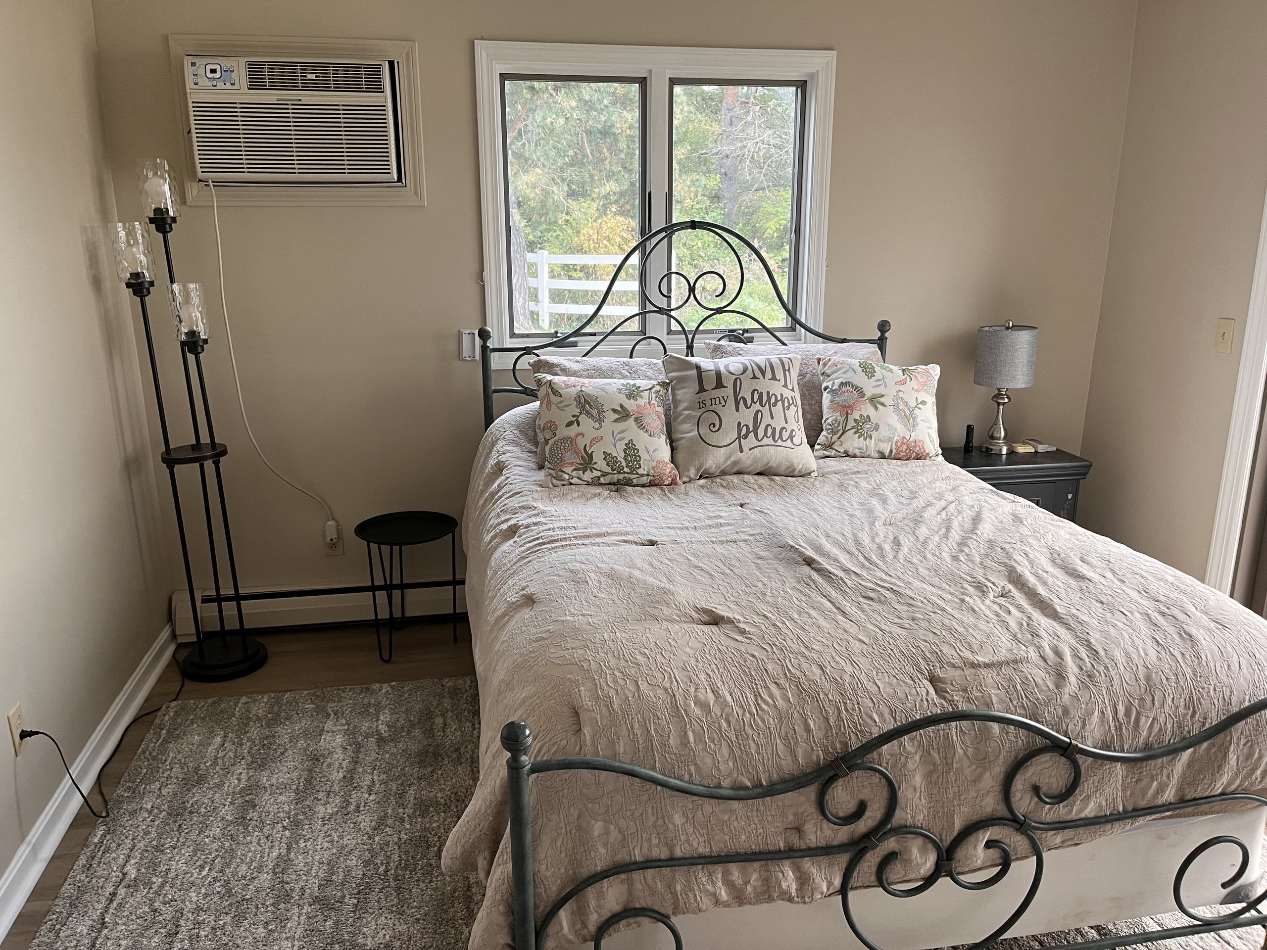Cozy bedroom corner with floral throw pillows and a forested window