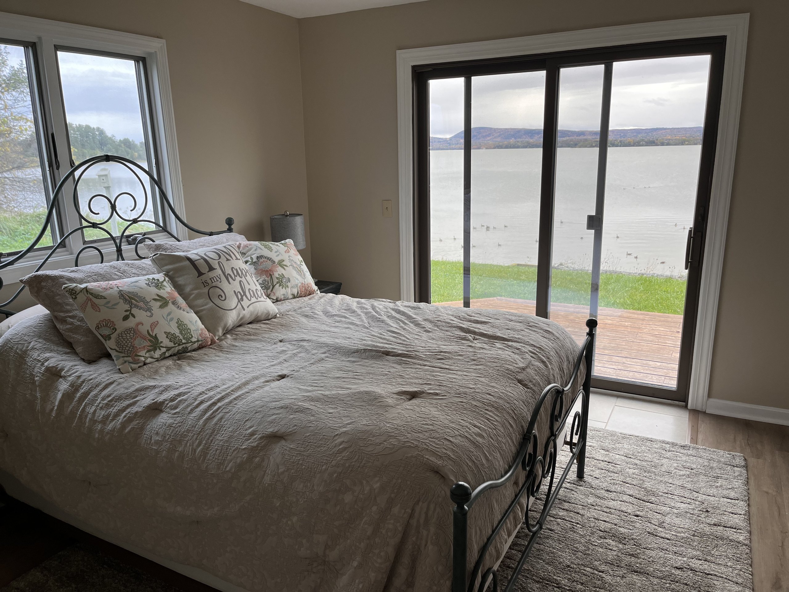 Lakefront bed with sliding doors open to grass, water, and ducks